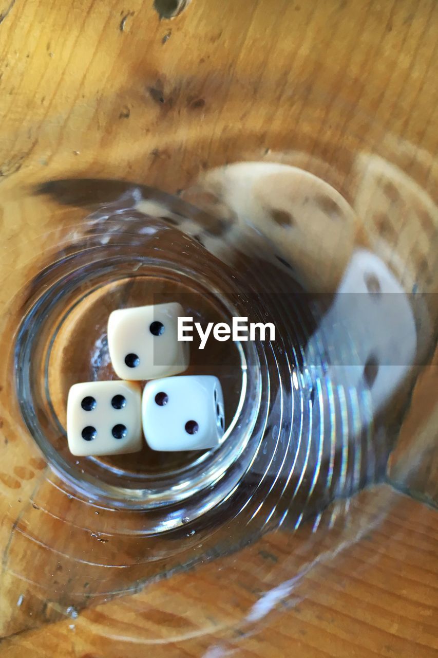 High angle view of dice in drinking glass on wooden table