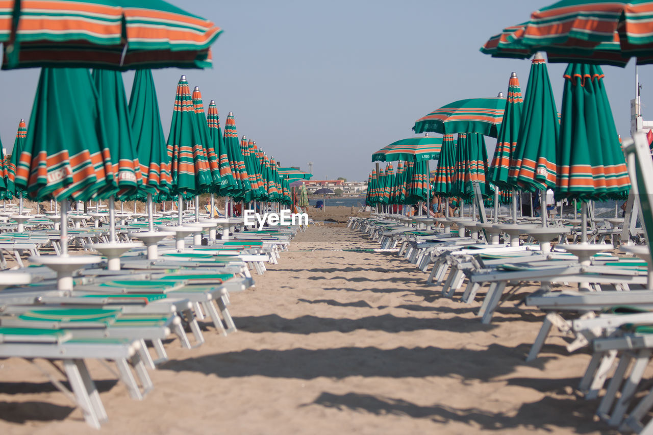 Lounge chairs on beach against sky