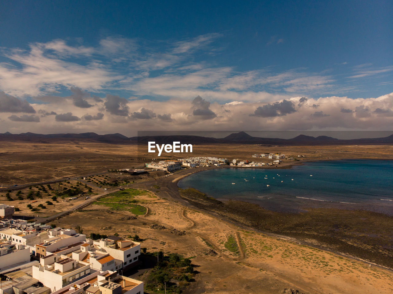 Aerial view of city by sea against sky