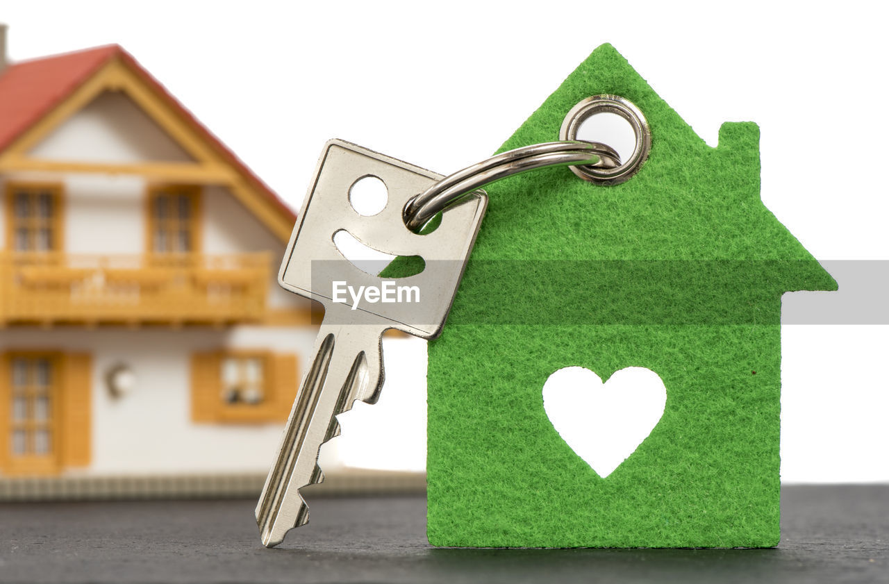 Close-up of model home with key on table against white background