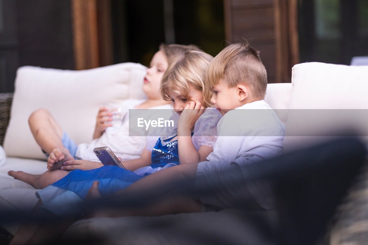 Boy and girls sitting on sofa at home