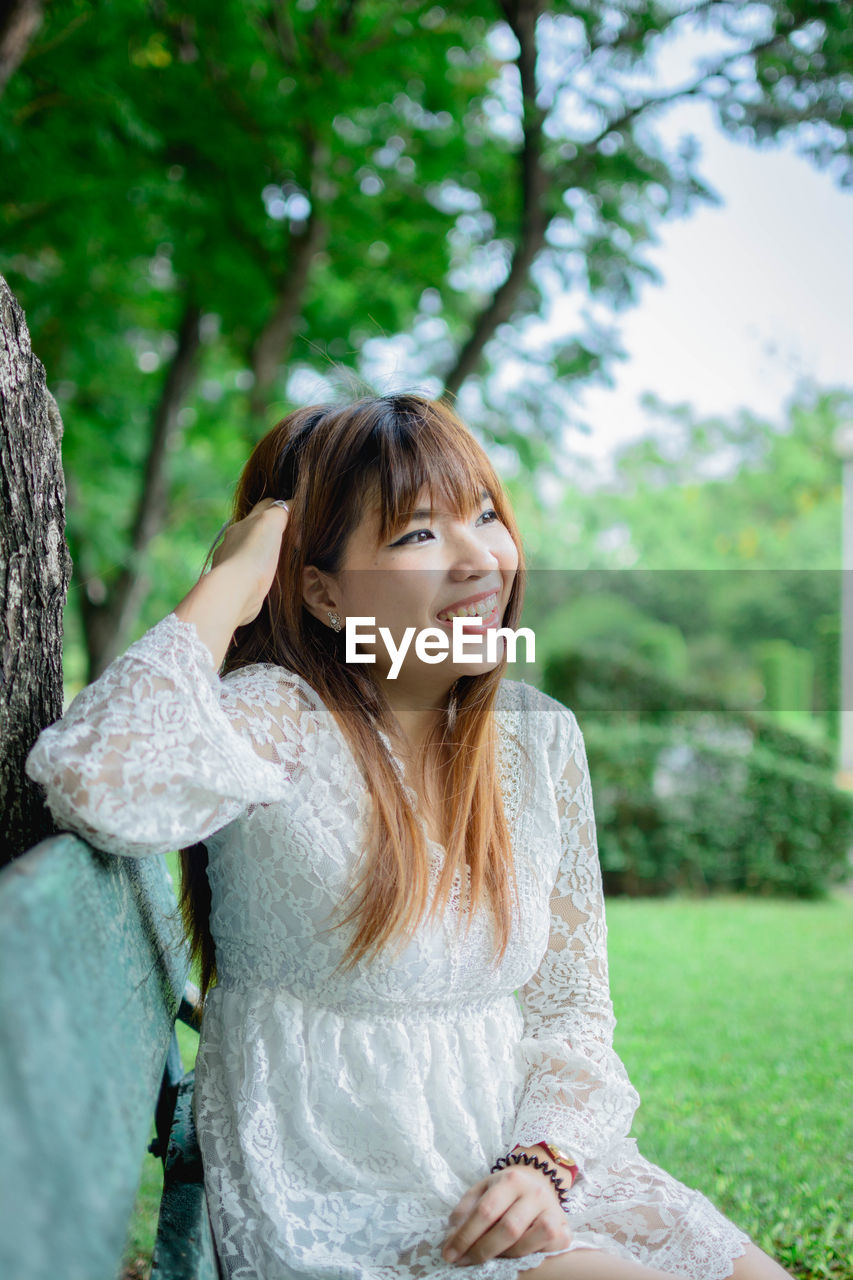 Smiling woman looking away while sitting in park