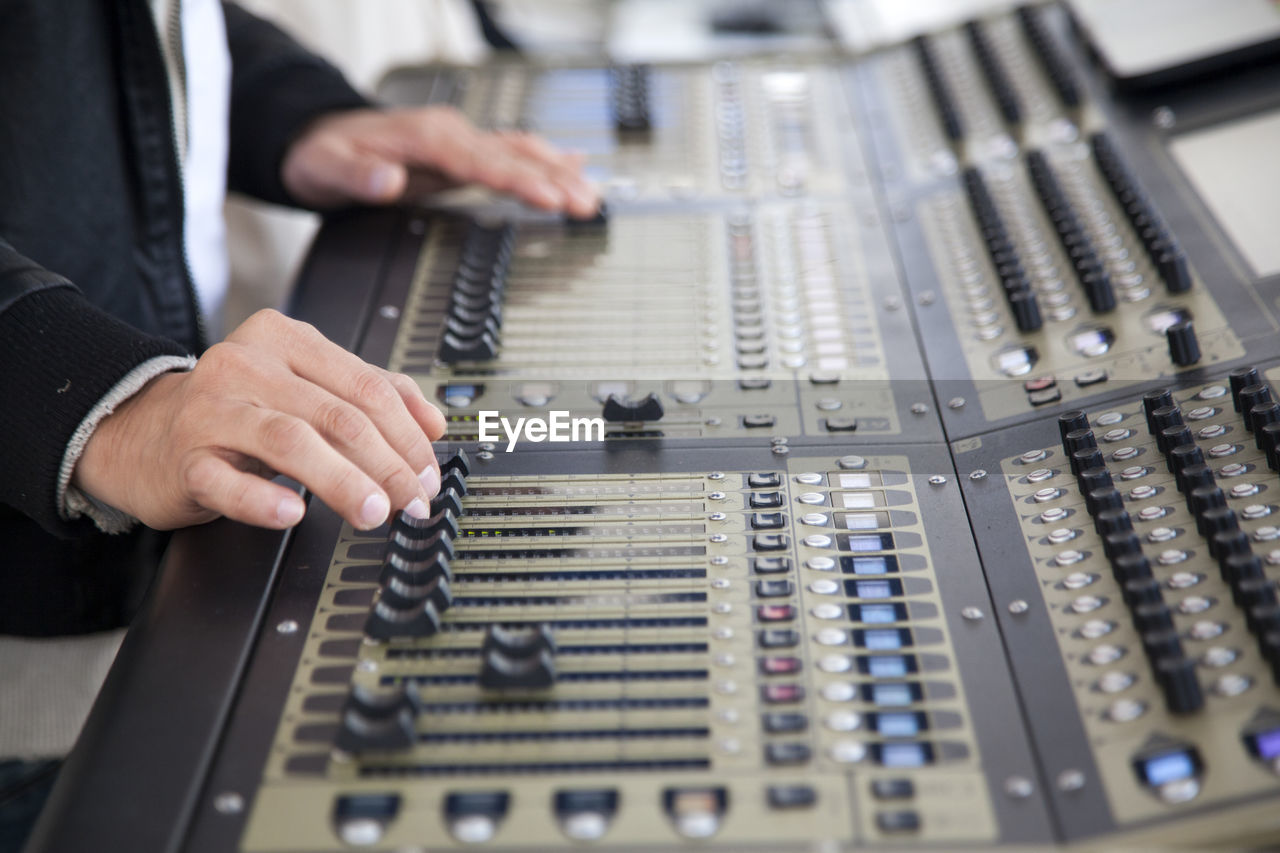 Technician adjusting sound mixers at studio