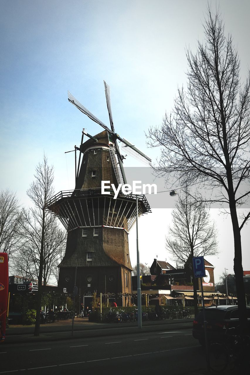 TRADITIONAL WINDMILL BY TREES AGAINST SKY