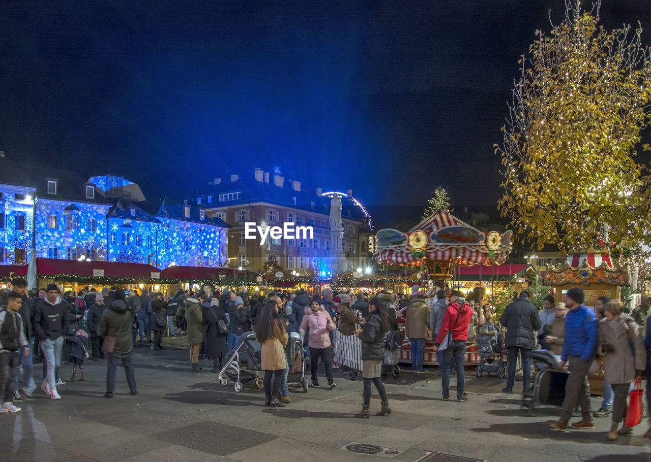 GROUP OF PEOPLE AT ILLUMINATED MARKET