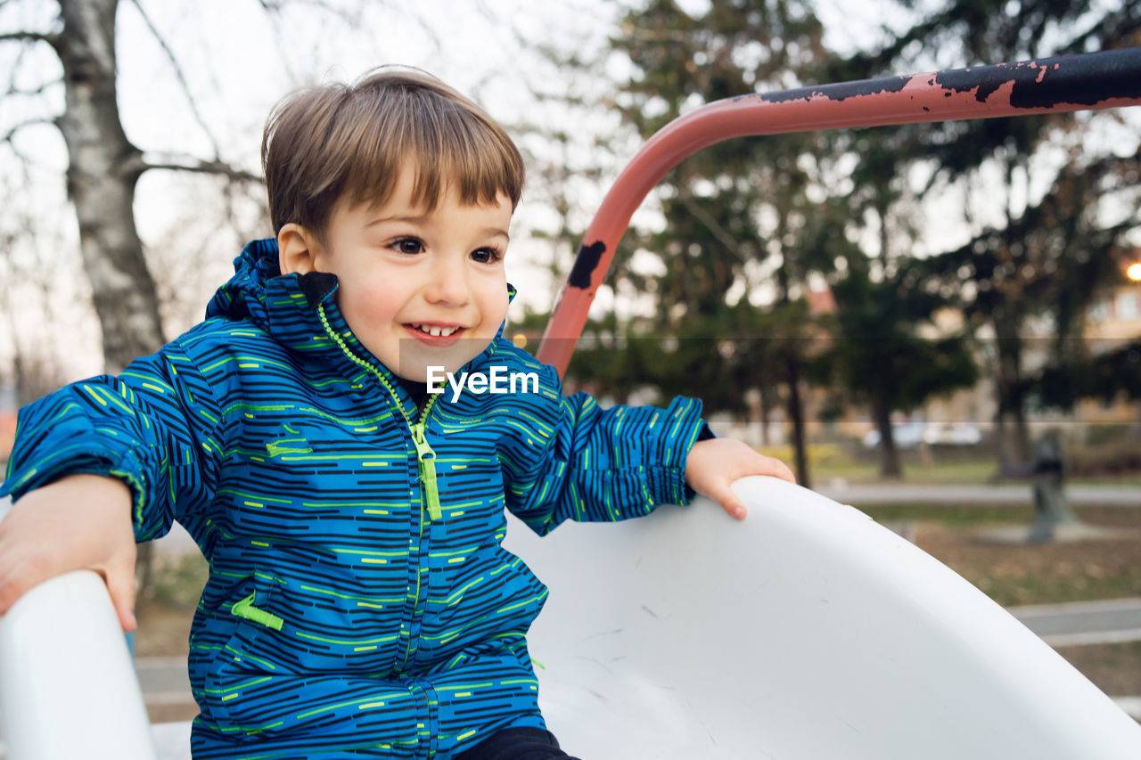 Cute boy playing on slide at playground