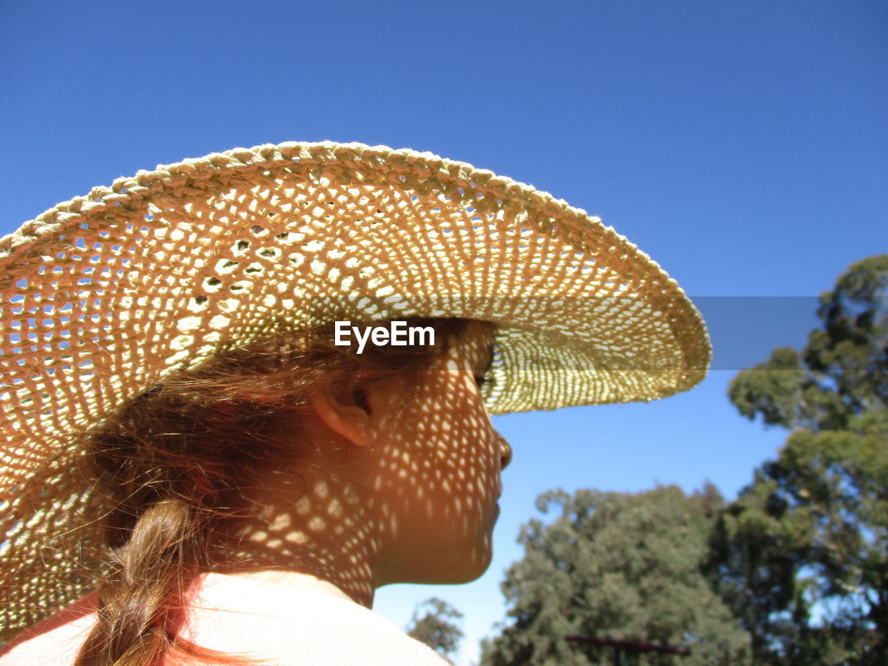 Rear view of girl wearing straw hat against clear blue sky on sunny day