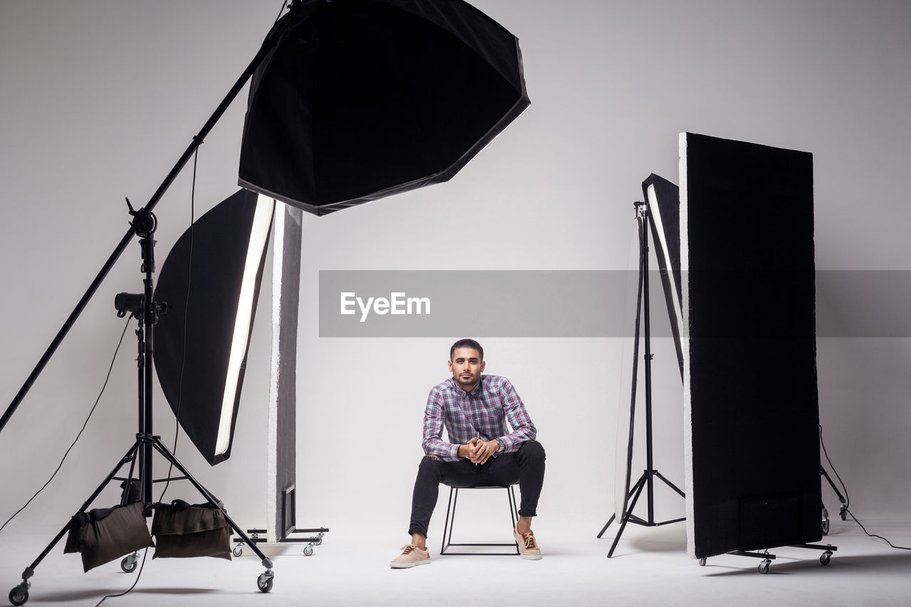 Full length portrait of young man photographing against white background