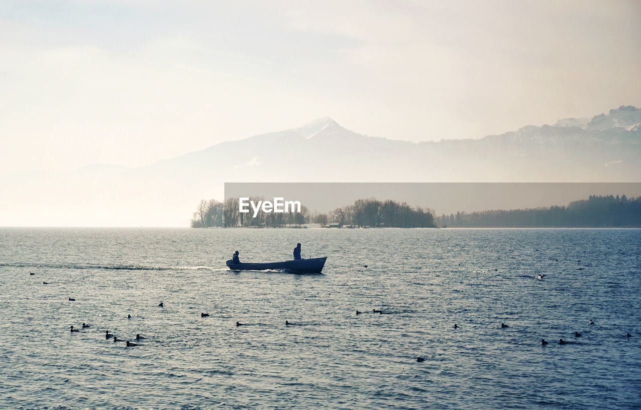 People on boat in sea against sky