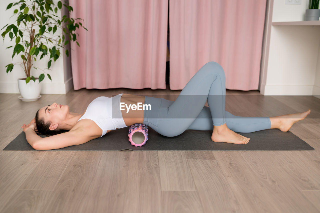 Female using foam roll before exercise to wake up the muscles as well as post-workout 