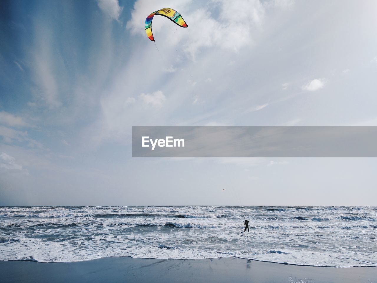 Person paragliding over sea against sky