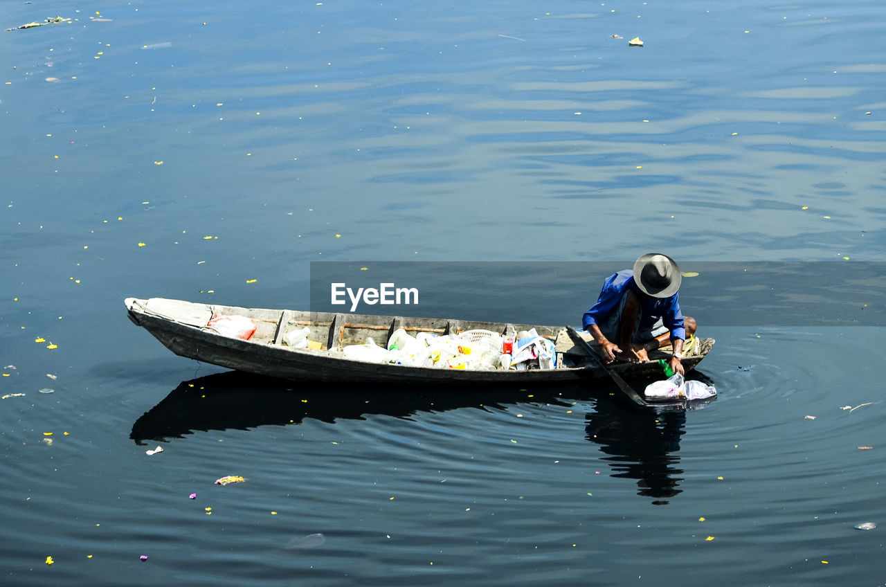 High angle view of man in boat collecting plastic