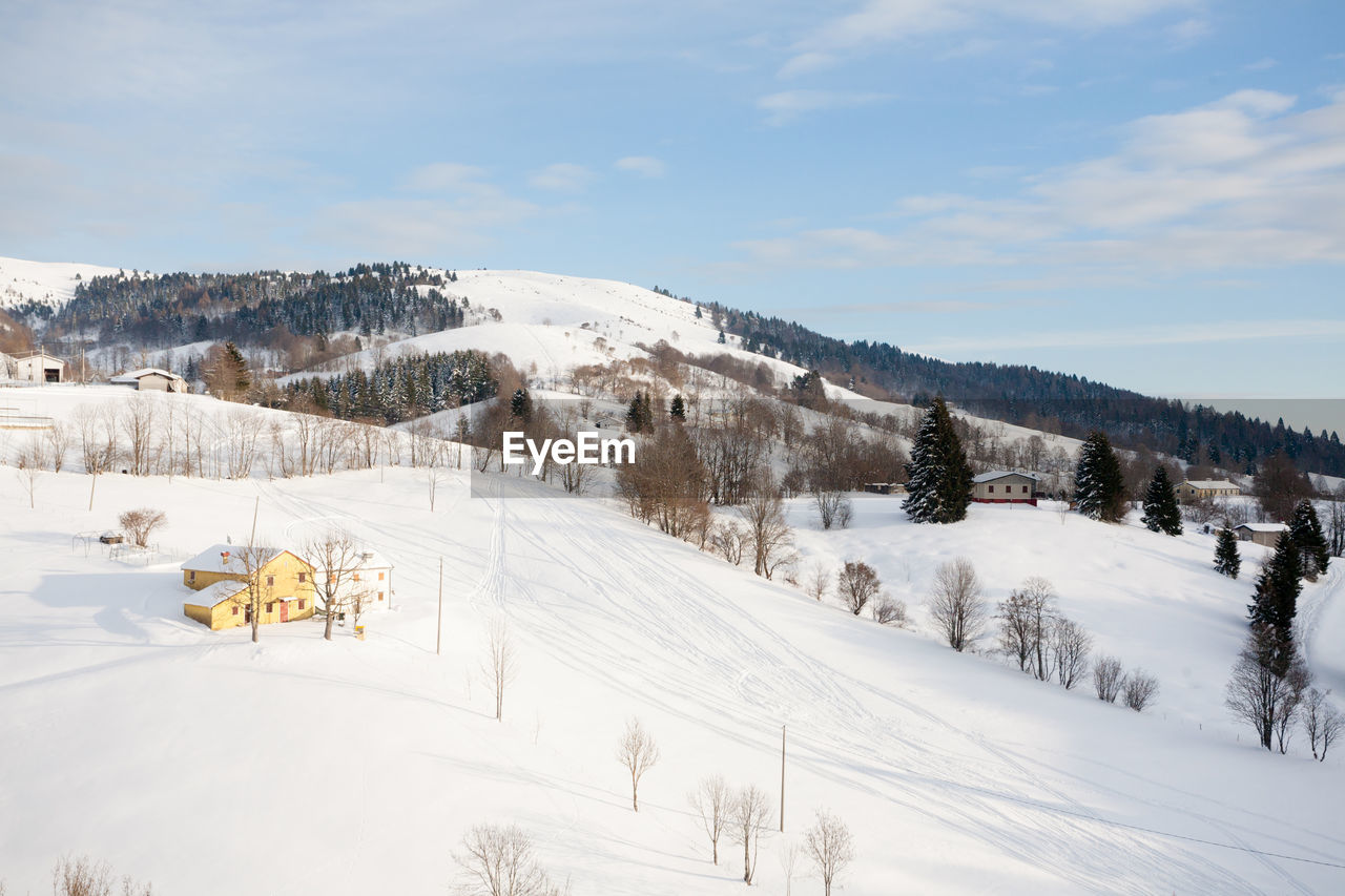 snow, winter, cold temperature, tree, scenics - nature, nature, sky, environment, mountain, beauty in nature, landscape, plant, piste, land, resort, forest, mountain range, cloud, white, footwear, tranquil scene, skiing, non-urban scene, pine tree, architecture, winter sports, day, travel, tranquility, coniferous tree, travel destinations, ski equipment, outdoors, nordic skiing, frozen, woodland, snowcapped mountain, pinaceae, sports, ski, building exterior, built structure, pine woodland, building, holiday, idyllic