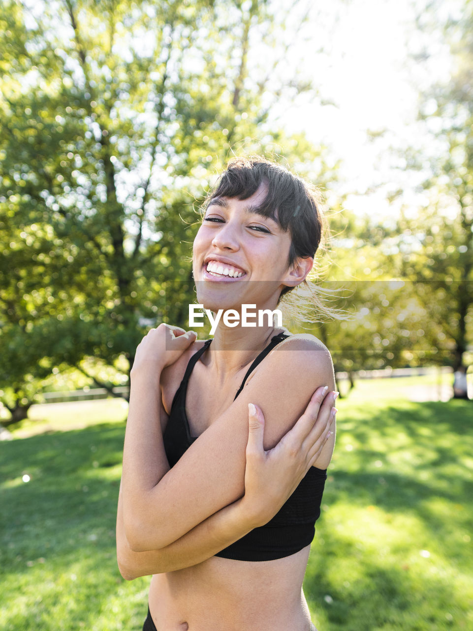 Happy young athlete hugging self in park