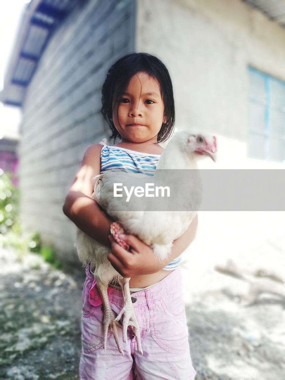 PORTRAIT OF A GIRL STANDING AGAINST BLURRED BACKGROUND