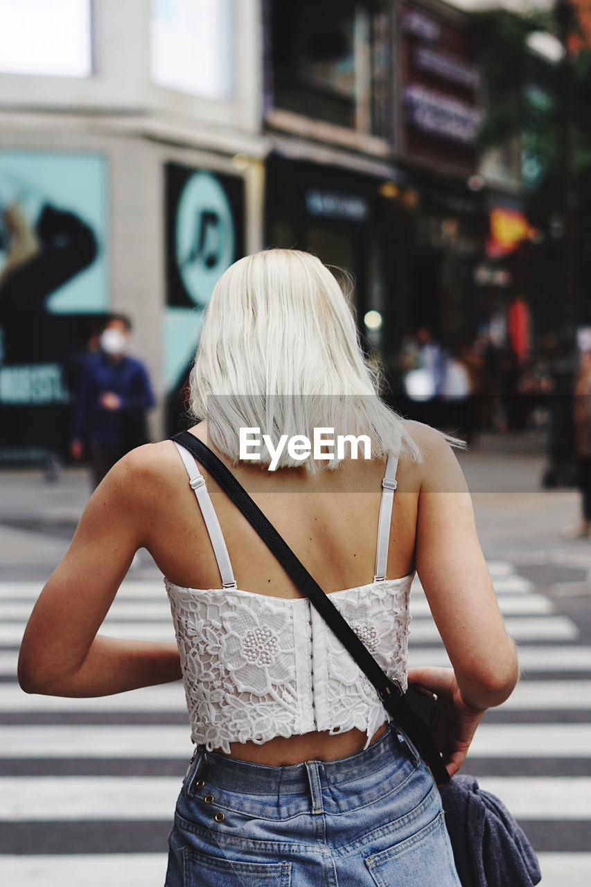 Rear view of woman standing on street in city