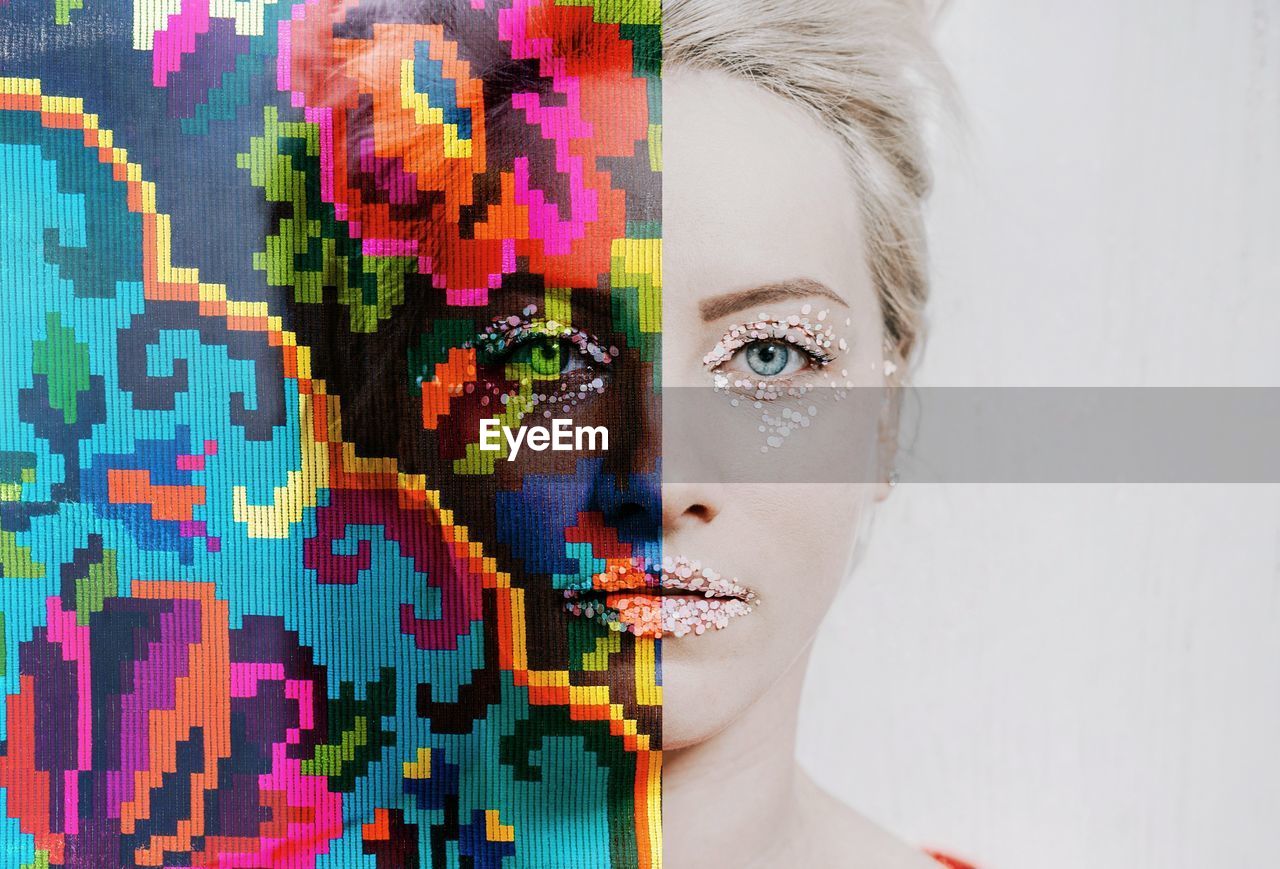 Digital composite image of woman with make-up and colorful pattern against wall