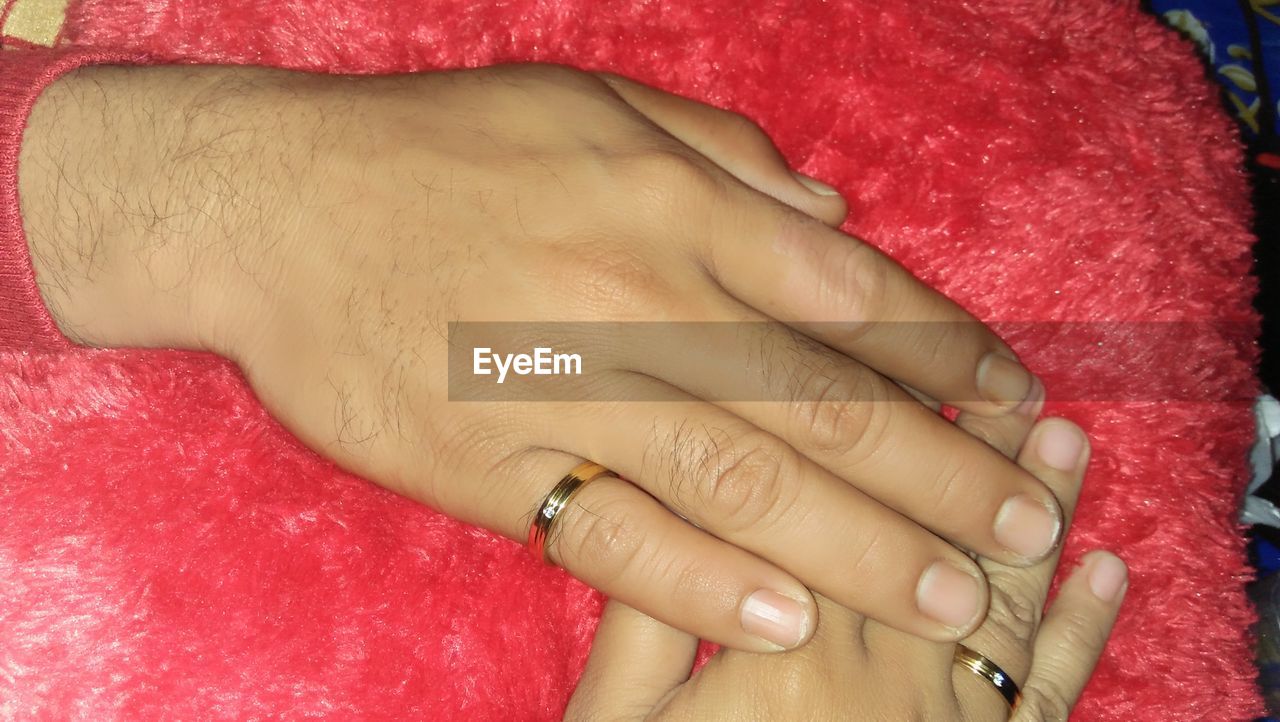 CLOSE-UP OF WOMAN HAND WITH RED PETALS ON FINGER