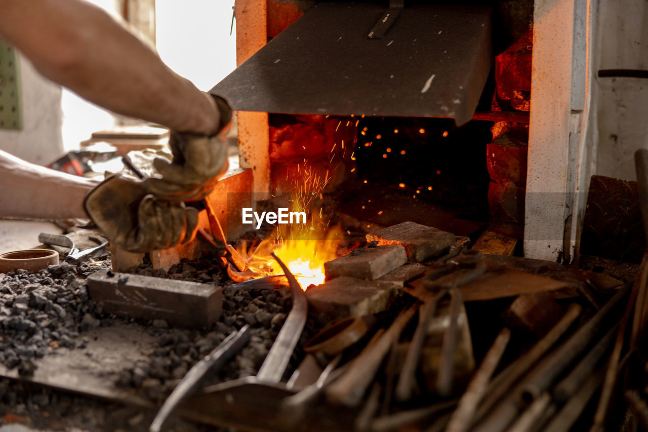 The blacksmith in production process of metal products, handmade in the forge. craftsman heats metal