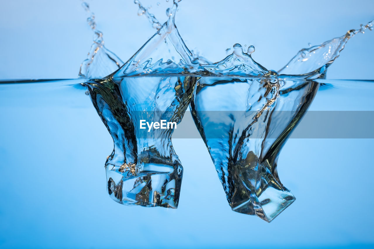 CLOSE-UP OF GLASS AGAINST BLUE BACKGROUND