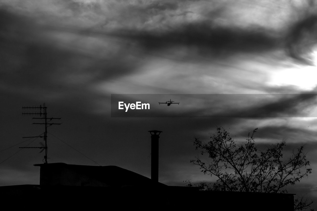 Low angle view of silhouette airplane flying against sky