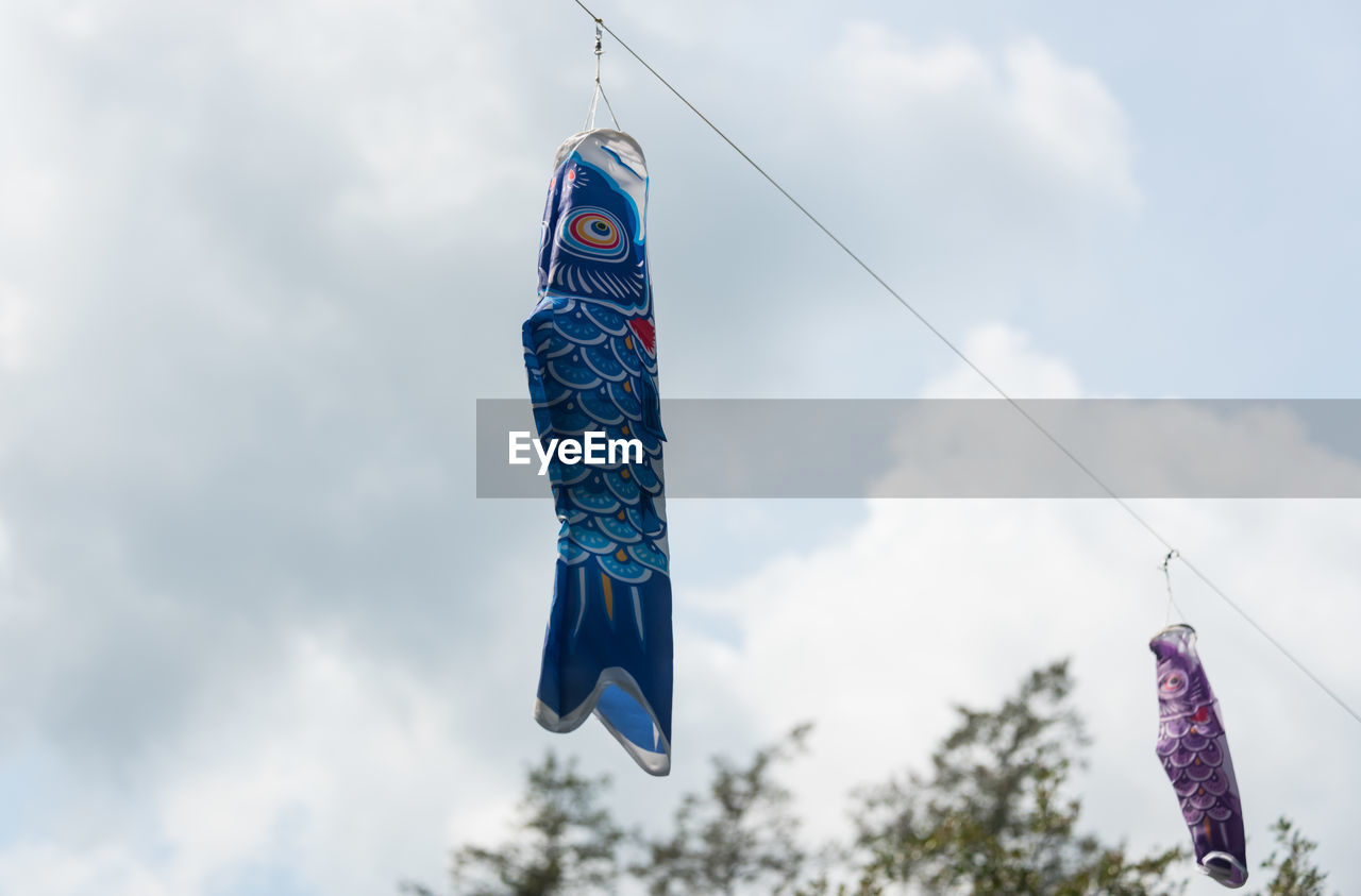 LOW ANGLE VIEW OF FISH HANGING FROM AGAINST SKY