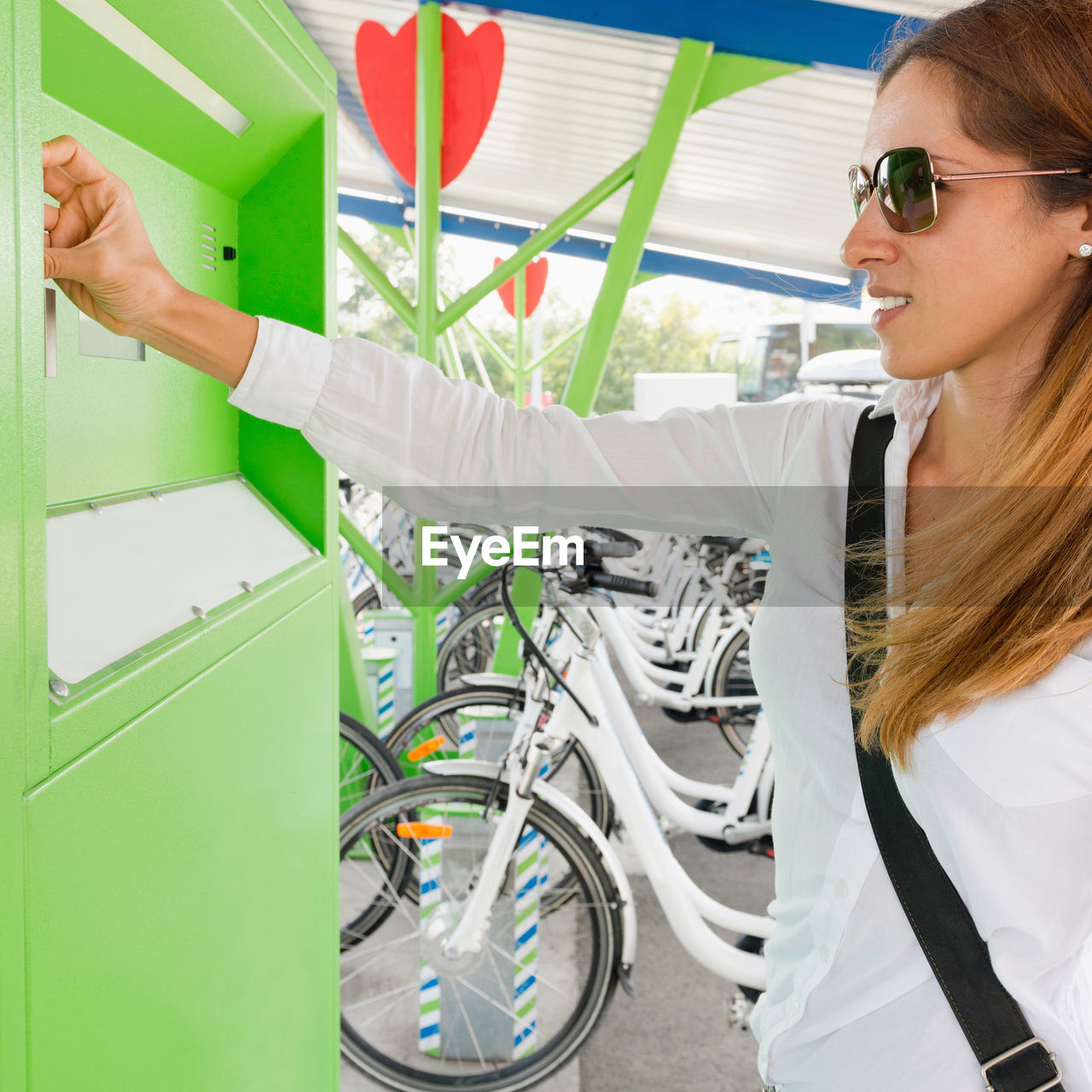 Businesswoman using machinery at bicycle sharing system