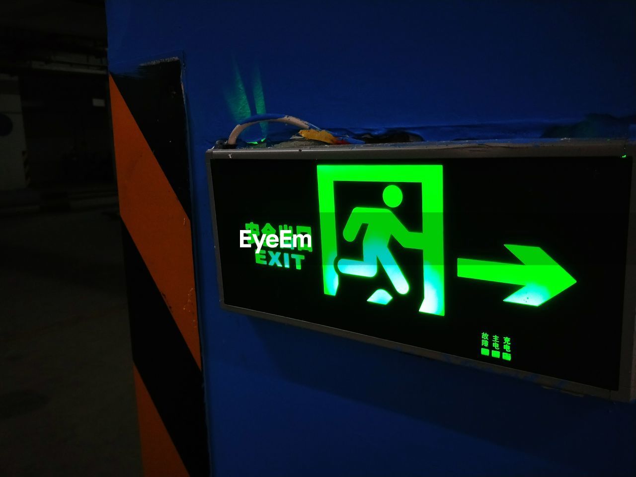 Close-up of illuminated exit sign on wall