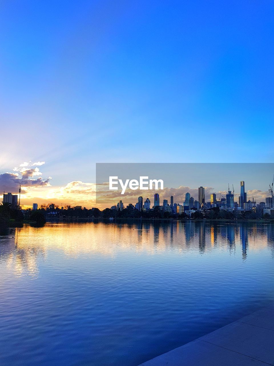 Scenic view of lake by buildings against blue sky