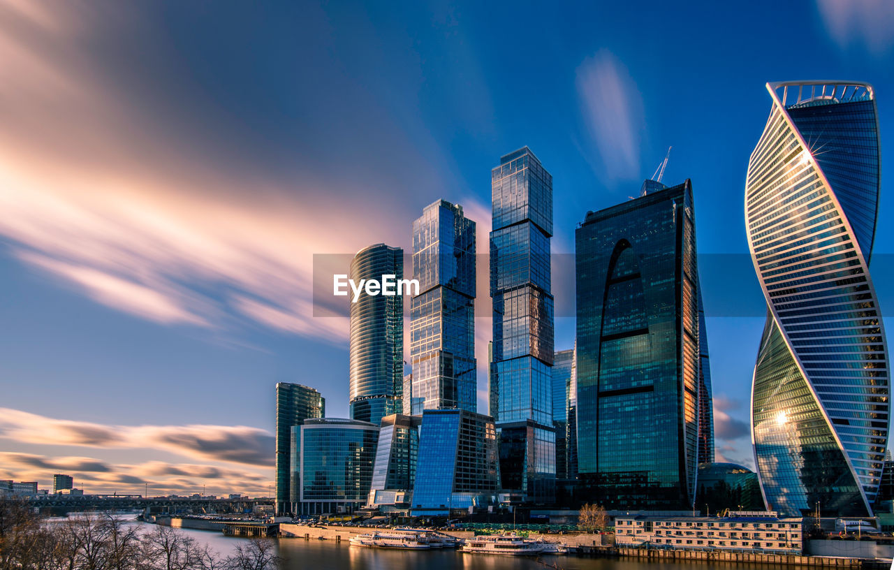 Low angle view of skyscrapers against cloudy sky