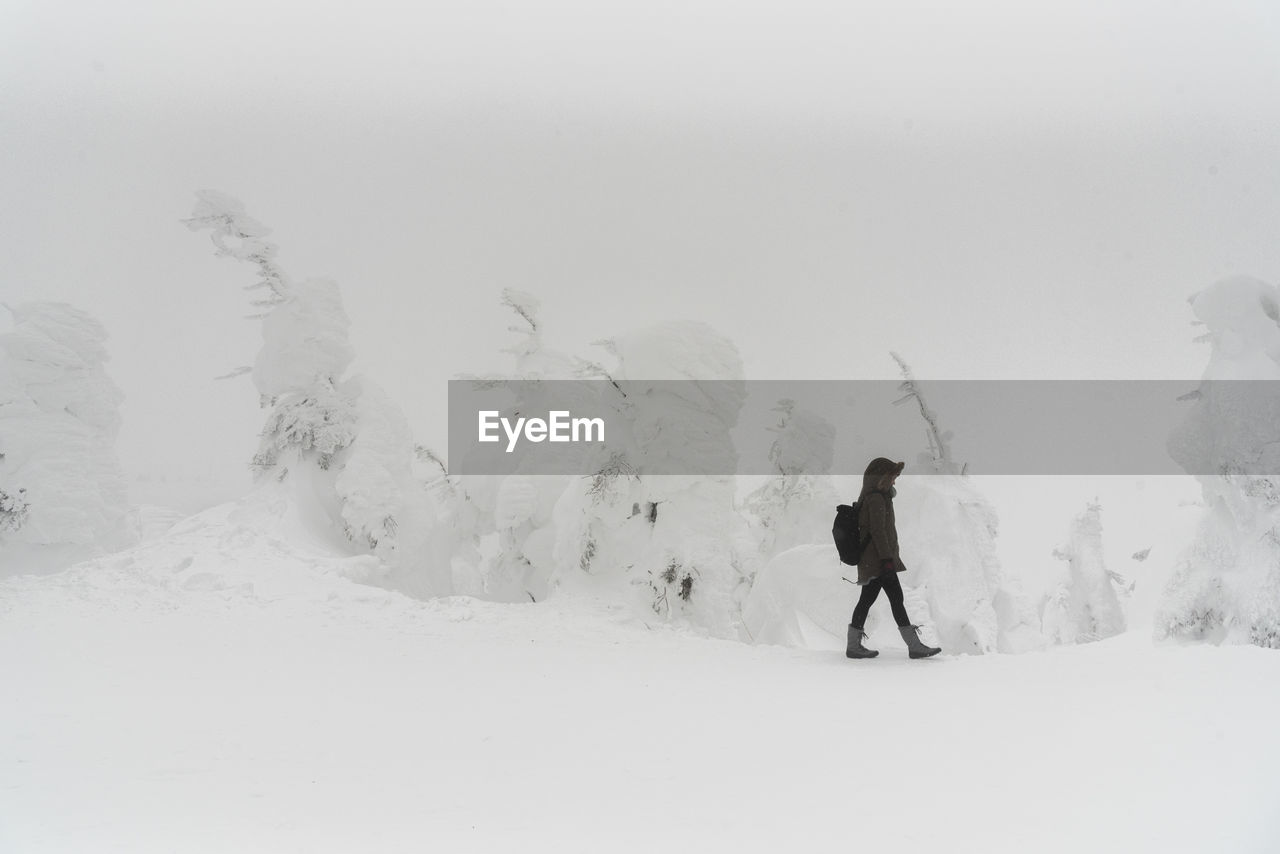 Full length of woman walking on snow covered landscape