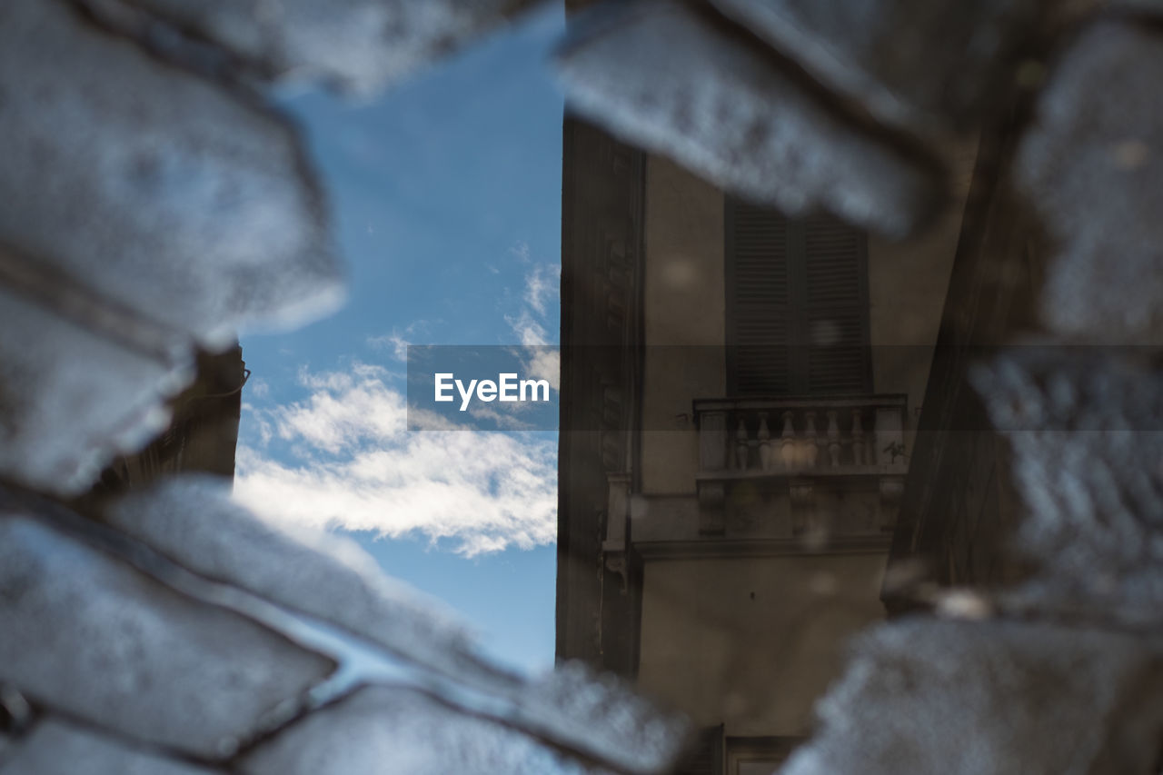 Reflection of building and sky in puddle on street