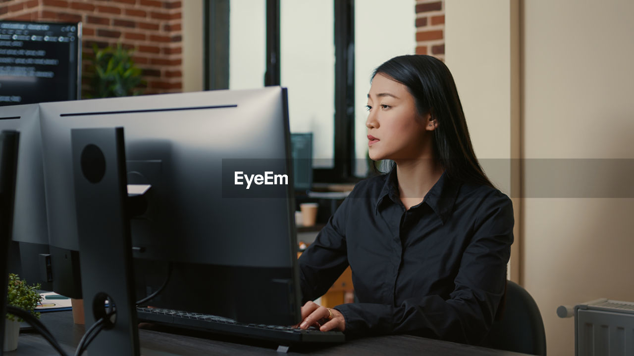 portrait of young woman using laptop while sitting in office