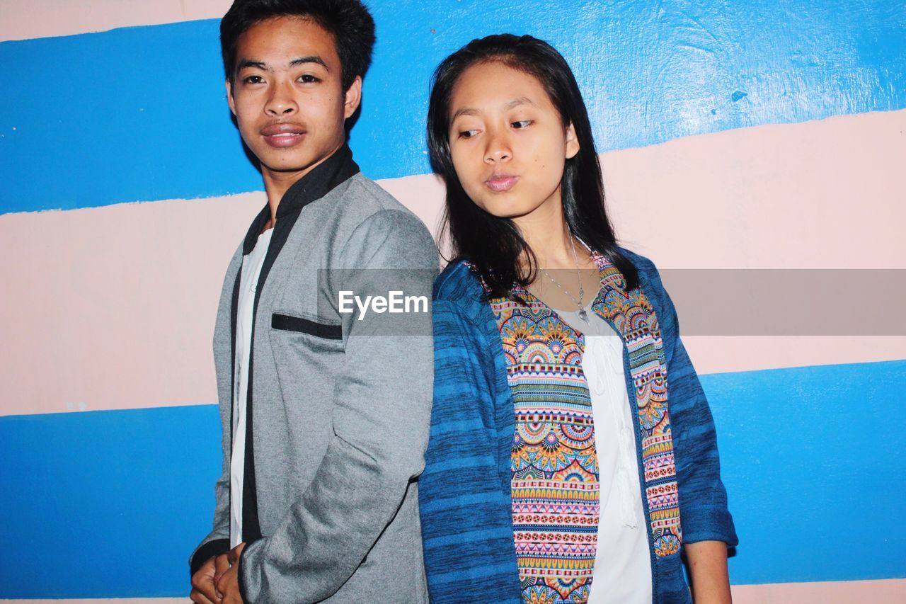 Young couple standing against blue wall