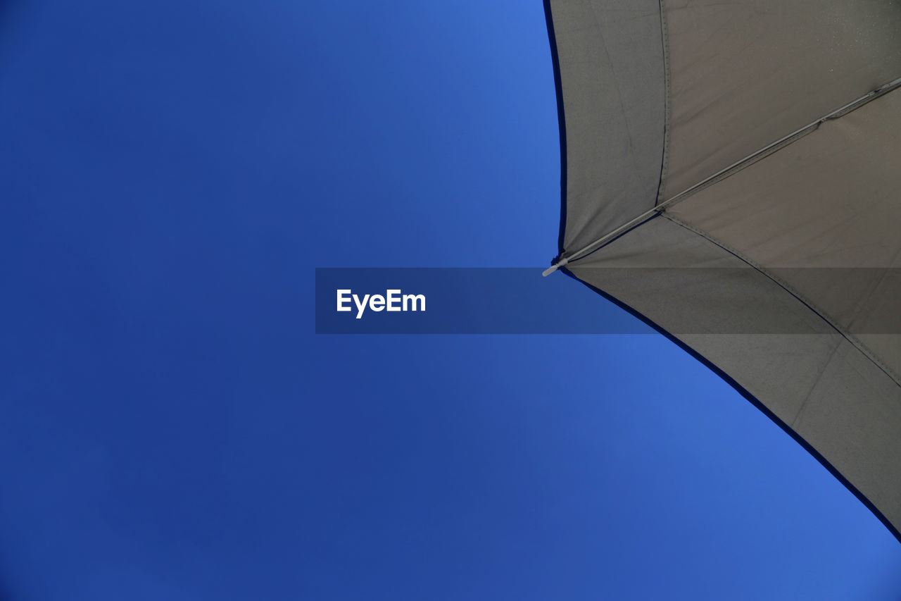 Low angle view of beach umbrella against clear blue sky