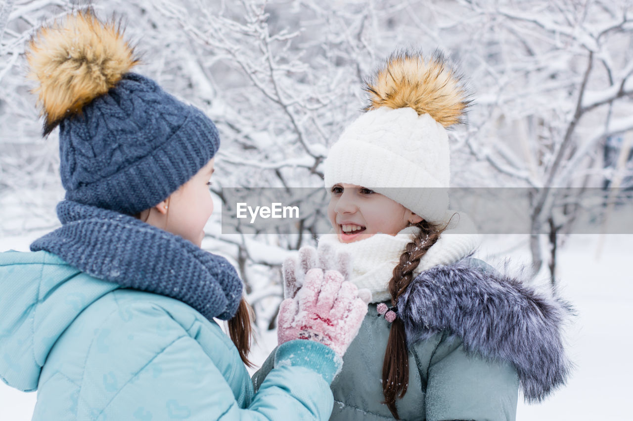 Two smiling girls in warm clothes met in a snowy park. winter walks, lifestyle