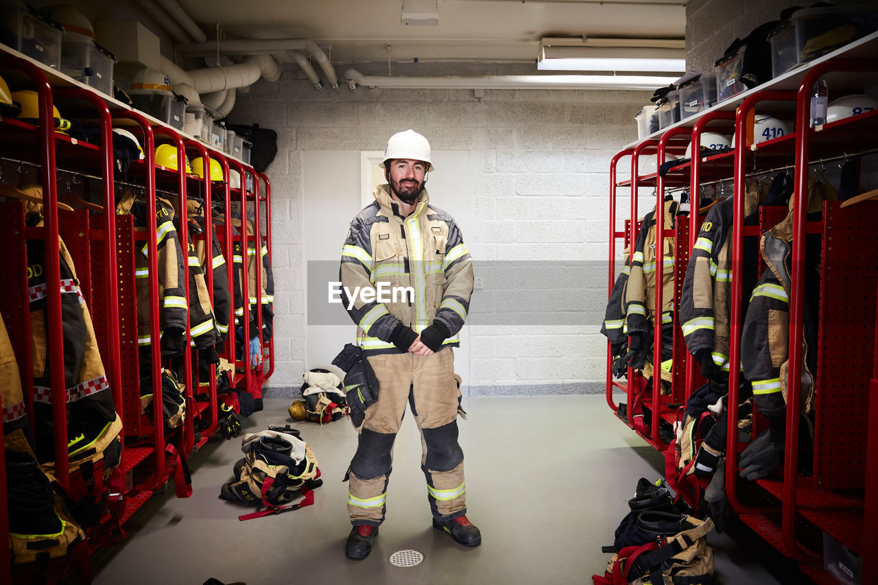 Full length of male firefighter standing in locker room at fire station