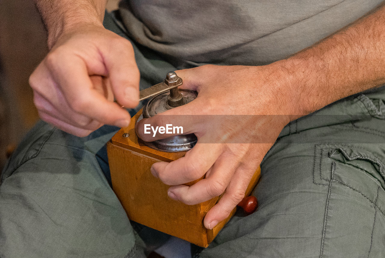 Midsection of man holding coffee grinder