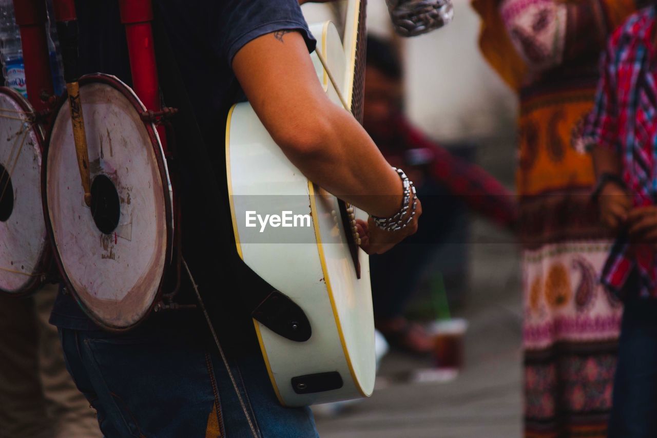 Midsection of person playing guitar outdoors