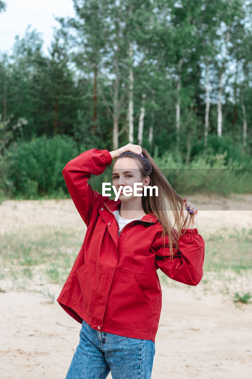 Candid portrait of a young caucasian woman in red clothes playing with her hair, posing