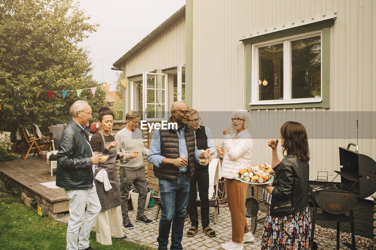 Active senior men and women enjoying dinner party at back yard