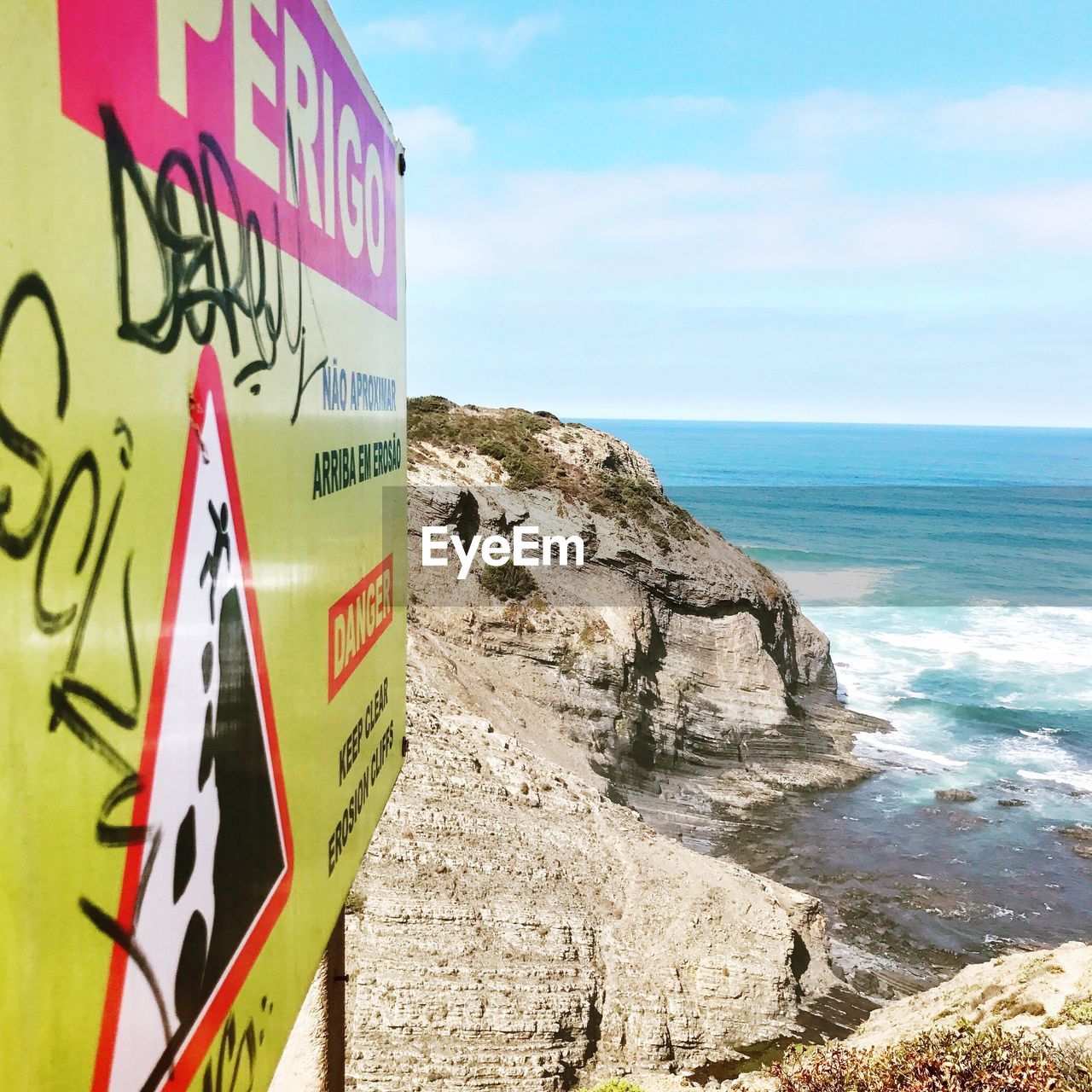 CLOSE-UP OF ROAD SIGN AGAINST SEA