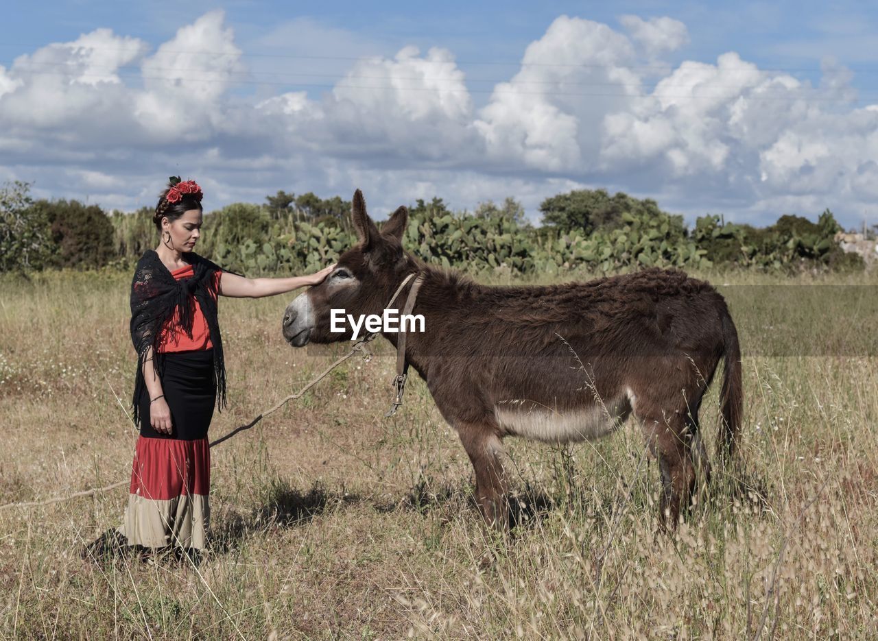 Woman standing with donkey in field
