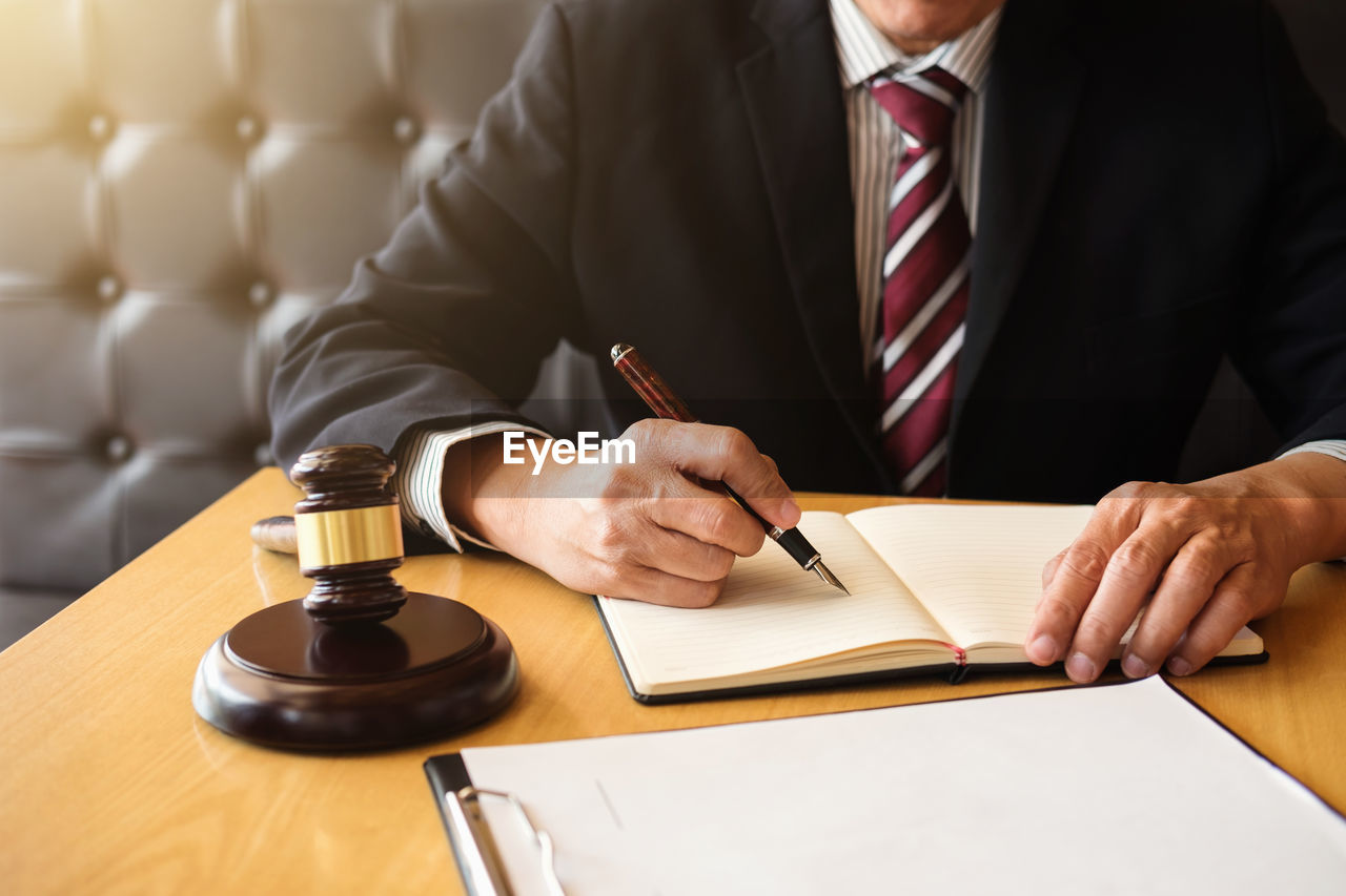 Midsection of lawyer working on desk at office