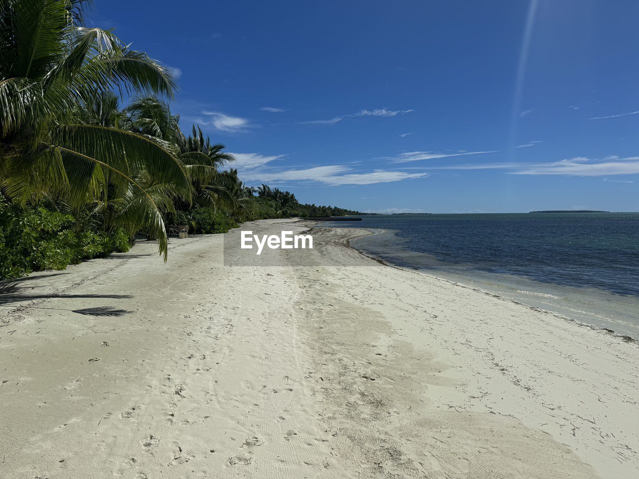 land, beach, sand, sky, sea, water, scenics - nature, nature, palm tree, beauty in nature, tropical climate, ocean, coast, shore, tree, tranquility, plant, body of water, environment, landscape, blue, tranquil scene, cloud, travel destinations, travel, coastline, holiday, vacation, no people, trip, outdoors, idyllic, island, tourism, horizon over water, horizon, coconut palm tree, day, tropical tree, summer, clear sky, sunlight, seascape, non-urban scene, bay, wave, water's edge, footprint, sand dune, sunny