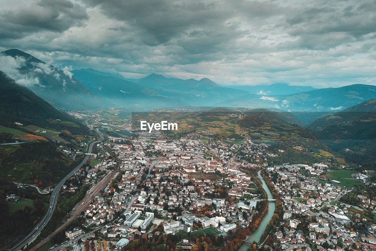 Aerial view of townscape and mountains against sky