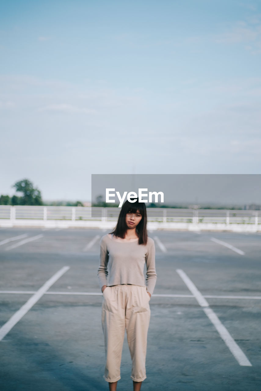 PORTRAIT OF WOMAN STANDING ON ROAD