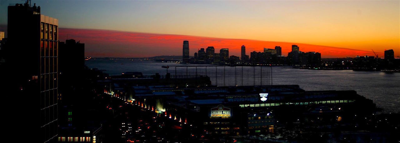 Panoramic view of silhouette city by hudson river against sky during sunset