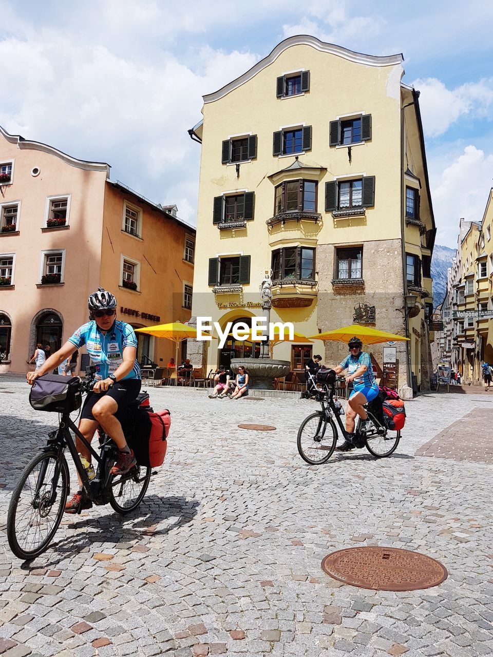 PEOPLE RIDING BICYCLE ON STREET AGAINST BUILDINGS