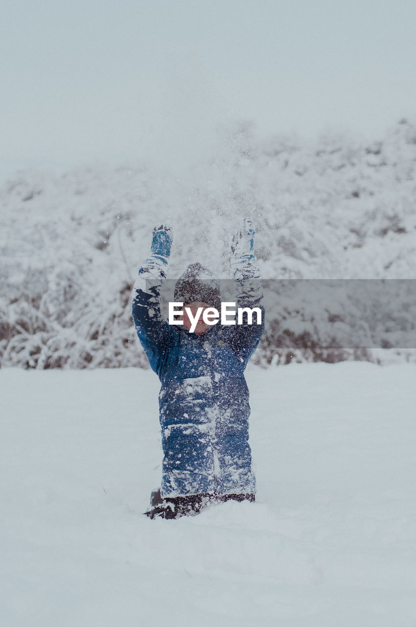 Boy standing on snow covered field